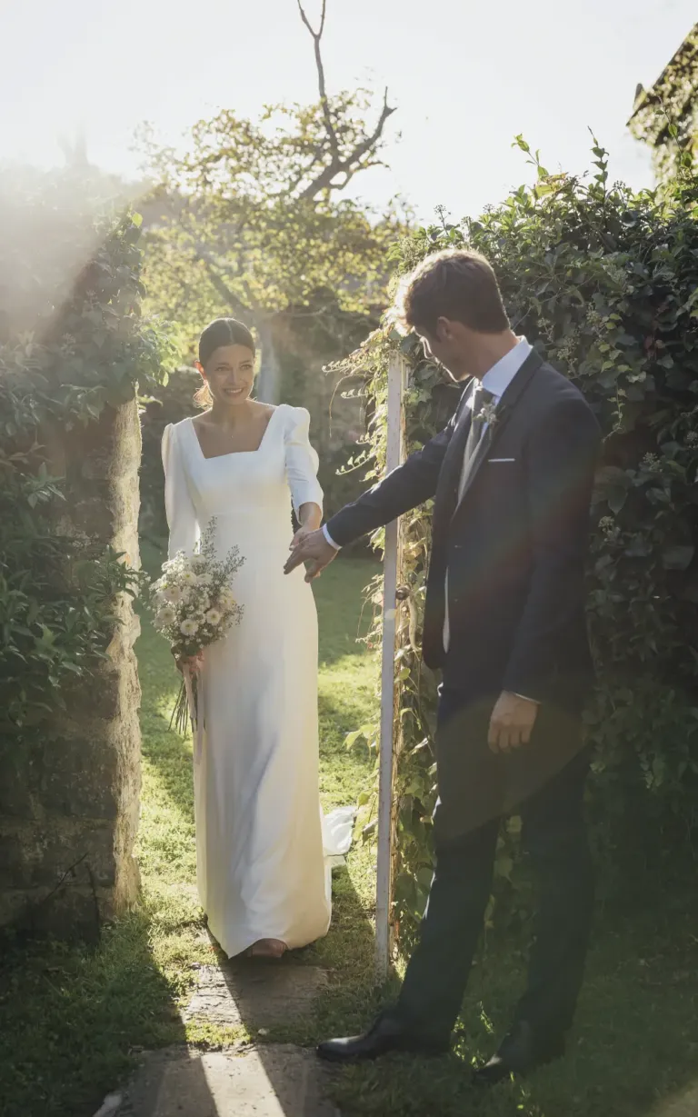 Pareja de novios entrando por una puerta de jardín